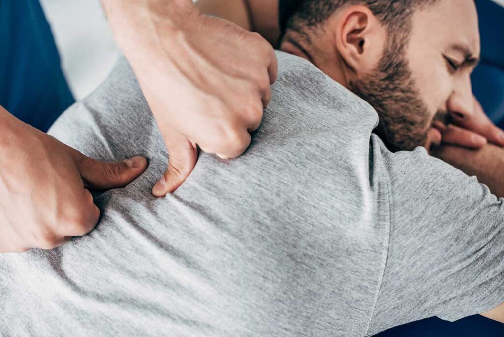 A chiropractor carefully performing a spinal adjustment on an adult patient in a bright, professional clinic.
